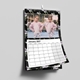 Personalised black floral A3 wall calendar hanging by its wire-bound hook with a large family photo.