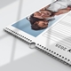 Close-up of a spiral-bound wall calendar for July 2025 lying on a flat surface. The visible photo shows a playful moment of a girl covering her smiling father’s eyes. The calendar's binding and hanging loop are clearly shown.