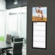 A customisable black kitchen calendar hangs on a dark wall in a modern office space. The August page is visible, featuring a a photo of your choice. Below, the calendar has ample space for notes and scheduling.