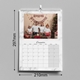 An A4 wall calendar for December 2025 with dimensions of 297mm width and 420mm height. The page features a family Christmas photo with festive decorations and a marble design border. The calendar includes a monthly grid, spiral binding, and a hanging hook.