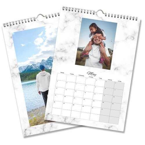 Two A3 wall calendars with marble-patterned borders. One features a landscape image of a person by a lake and mountains, while the other shows May 2025 with a photo of a man carrying a child on his shoulders. Both calendars have spiral bindings and hanging hooks.