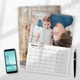 Personalised A3 March 2027 photo calendar displayed on a desk beside a smartphone and pen.
