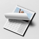 Open wall calendar lying flat, showing a partially turned page with a photo of a smiling young girl pointing up at the sky. The calendar features a clean white layout with a visible grid of dates below. The spiral binding and hanging hook are clearly seen at the top.