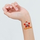 Close-up of a wrist displaying a red star-shaped temporary tattoo with a man's face and the words Happy Birthday! The tattoo stands out prominently against the skin, adding a festive touch.