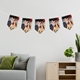 Personalised bunting with repeated photos of a smiling couple, hanging above a modern living room setting with a gray couch, green cushion, and a wooden side table holding potted plants.