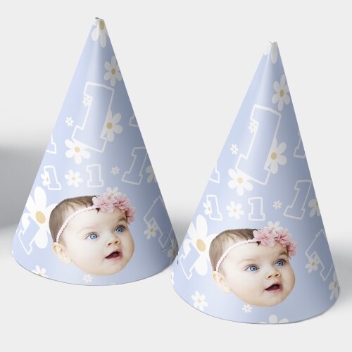 Two light blue personalised party hats featuring a baby girl's face with a pink floral headband, decorated with white daisies and the number 1, ideal for a first birthday celebration.