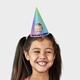 Smiling young girl wearing a customised party hat with a colourful gradient design, featuring a man's face and text reading Andrews 60th, perfect for birthday celebrations.