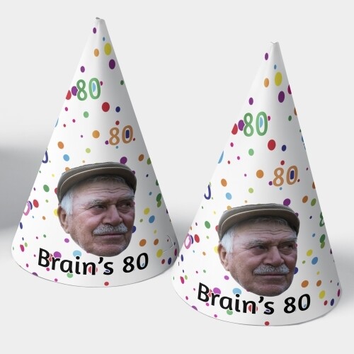 Two personalised party hats with a colourful polka dot design, featuring the text Brain's 80 and a photo of an elderly man wearing a flat cap. The cone-shaped hats are placed against a white background.