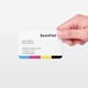 Rounded business card held in hand showing minimalist contact details layout with CMYK colour strip