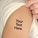 Personalised black text temporary tattoo applied to shoulder skin