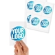 Transparent custom rectangle label sticker with a blue and white logo, shown on a fingertip, alongside two sheets filled with multiple identical stickers. Ideal for personalised branding or product labelling