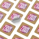 A sheet of square custom stickers with kraft backgrounds featuring bold text in pink, white, and yellow. One sticker is partially peeled, showcasing its adhesive backing. Ideal for personalised branding and labelling.