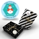 A set of 37mm circle Christmas labels featuring a snowman design with the text Merry Christmas. Two black and white wrapped gifts, one with stripes and one with polka dots, are shown with personalised labels tied with gold string. The label sheet includes 35 labels.