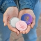 An open hand holding 3 custom pocket mirrors